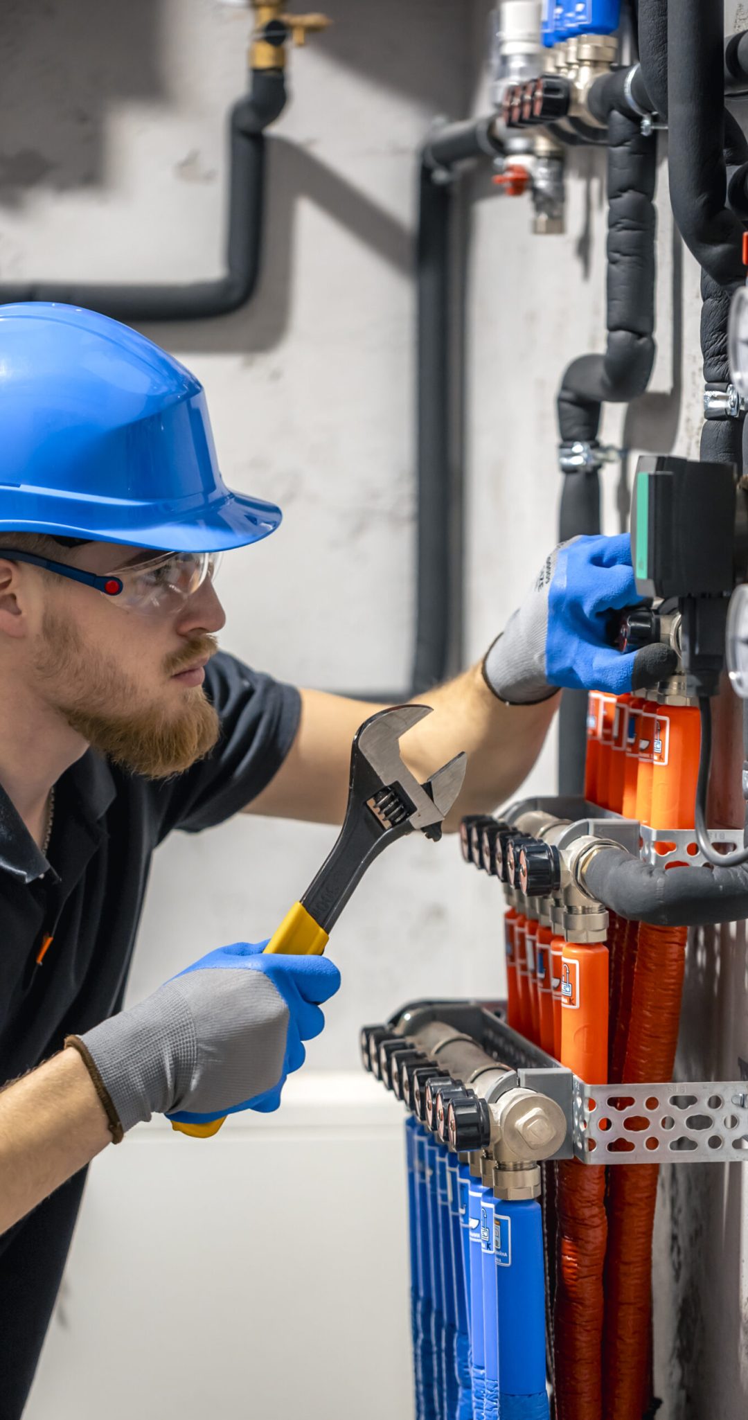 The technician checking the heating system in the boiler room. Adjusting heating valves in a residential building. A plumbing and heating technician works.